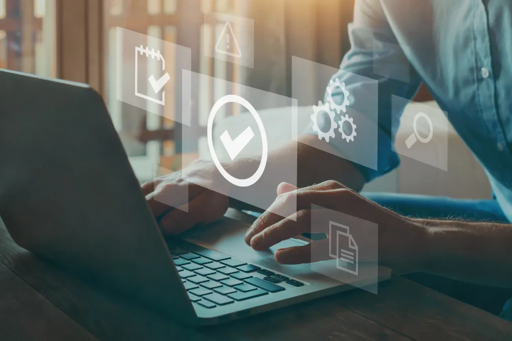 Mains sur le clavier d’un ordinateur portable, icônes de documents et de validation