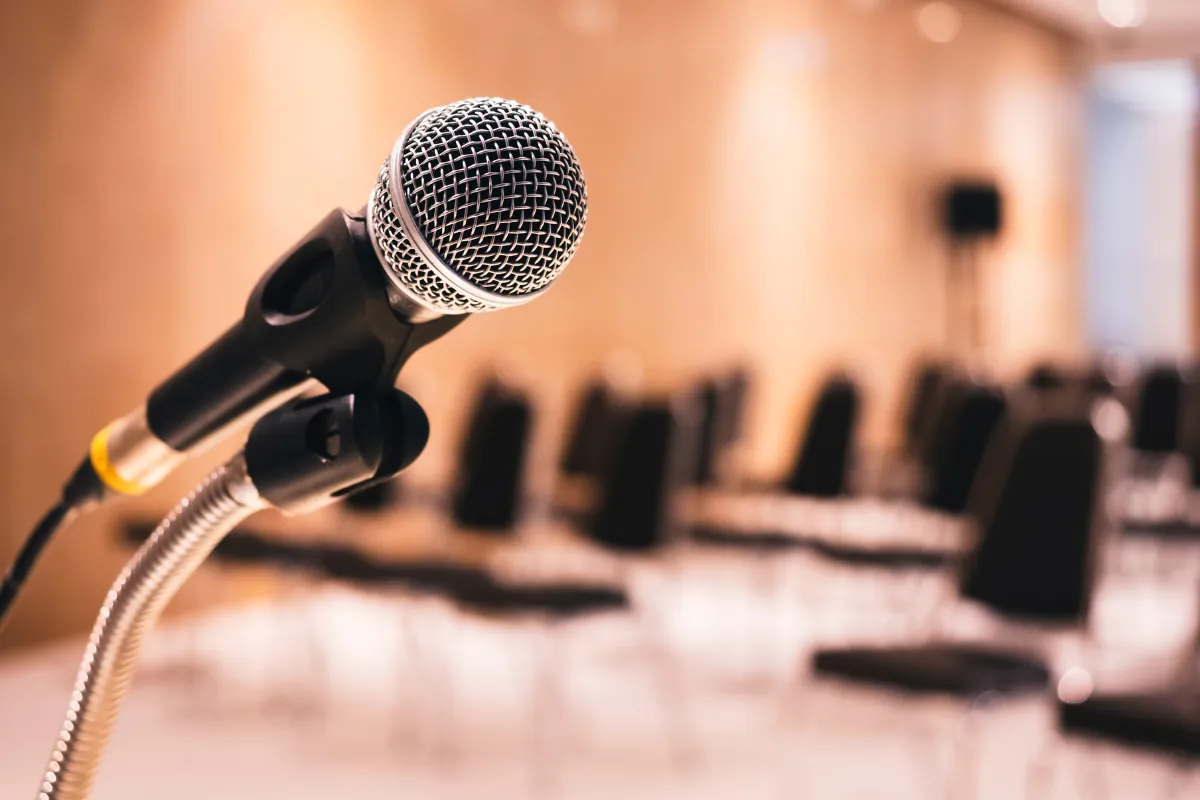 Microphone sur pied devant une salle aux chaises vides